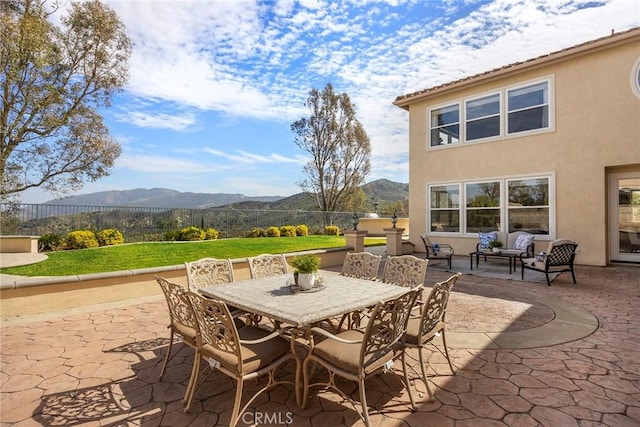 view of patio / terrace featuring outdoor dining area, a mountain view, and fence