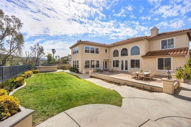 back of property with french doors, a yard, a chimney, and stucco siding