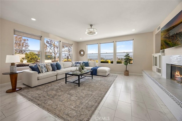 living room featuring a premium fireplace, baseboards, and recessed lighting