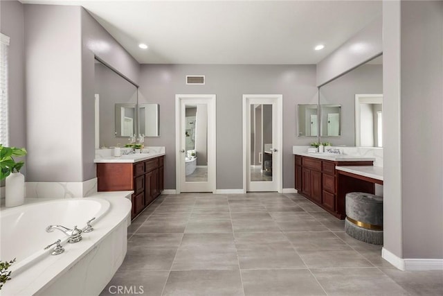 bathroom with a sink, two vanities, a garden tub, and visible vents