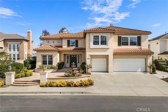 mediterranean / spanish-style house featuring concrete driveway, a tile roof, an attached garage, and stucco siding