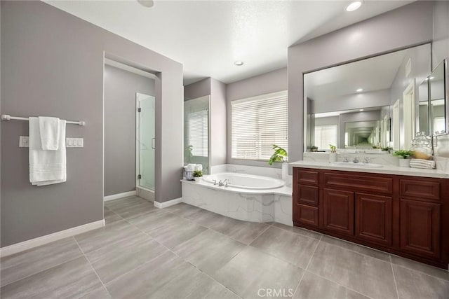 bathroom with vanity, baseboards, a shower stall, a bath, and tile patterned floors