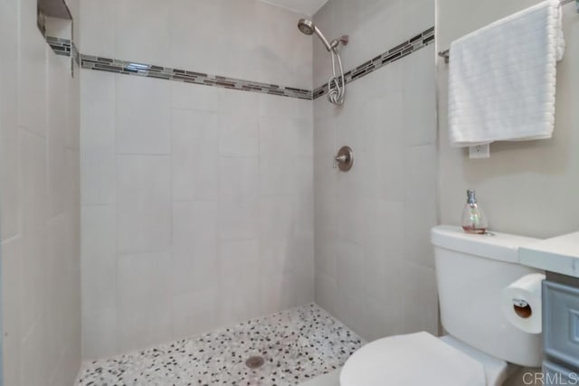 full bath with tiled shower and toilet