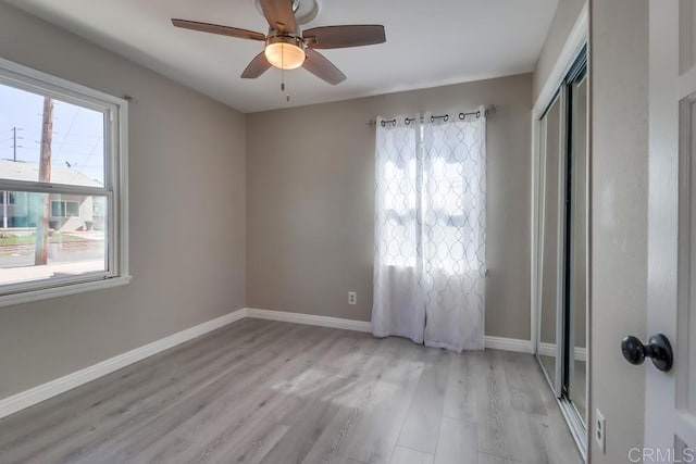 spare room featuring ceiling fan, light wood-type flooring, and baseboards