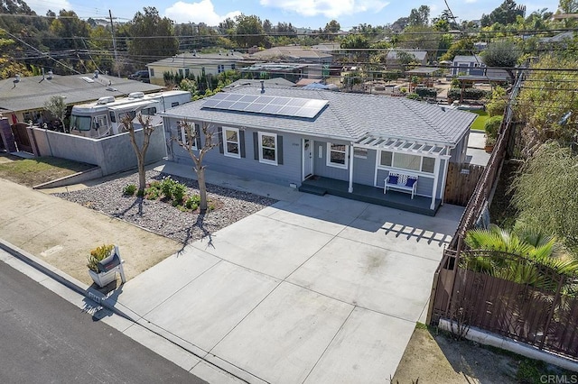 ranch-style house featuring solar panels, roof with shingles, and fence private yard