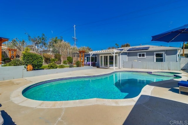 view of swimming pool featuring a patio, fence, a pool with connected hot tub, french doors, and a pergola