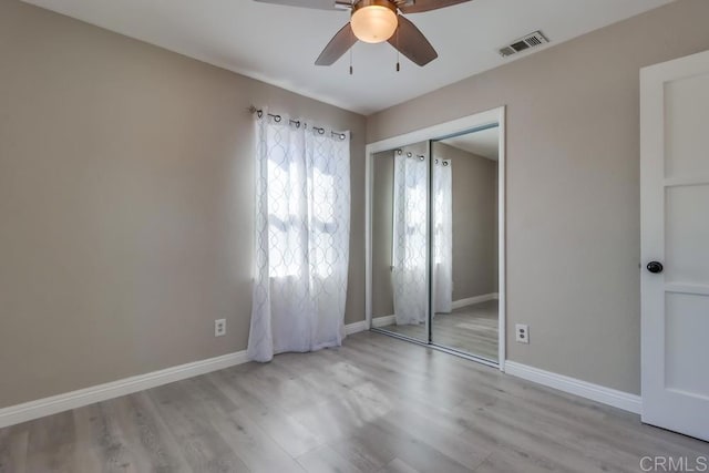 unfurnished bedroom with a closet, wood finished floors, visible vents, and baseboards