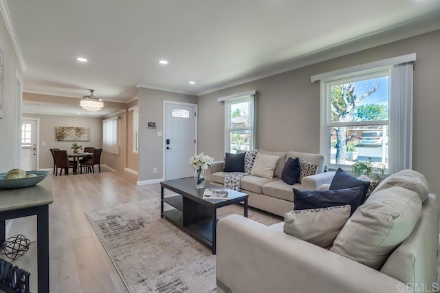 living area featuring light wood finished floors, ornamental molding, and a wealth of natural light