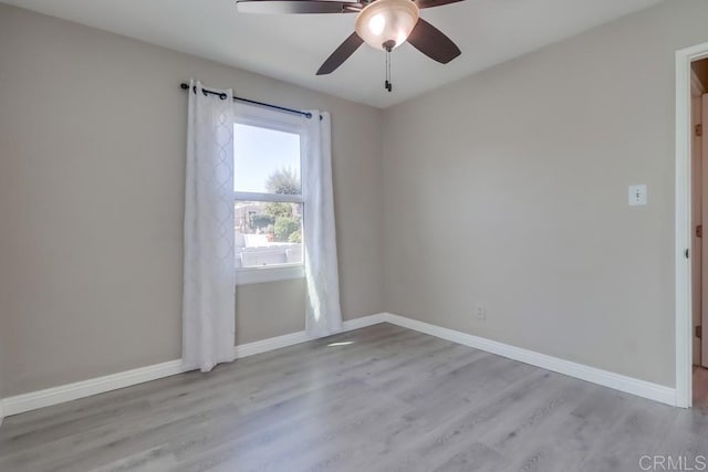 empty room featuring a ceiling fan, baseboards, and wood finished floors