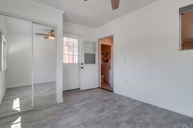 unfurnished bedroom featuring ceiling fan, ornamental molding, wood finished floors, and baseboards