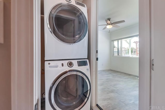 laundry area with stacked washer and dryer, laundry area, baseboards, ceiling fan, and ornamental molding