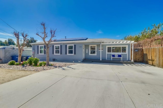 single story home featuring roof mounted solar panels and fence