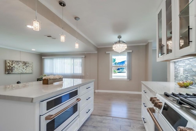 kitchen with visible vents, decorative backsplash, range with gas cooktop, ornamental molding, and decorative light fixtures