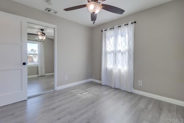 empty room featuring visible vents, ceiling fan, baseboards, and wood finished floors