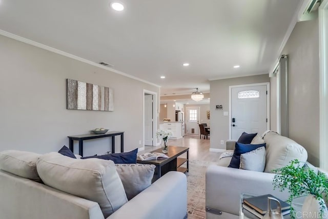 living area featuring ornamental molding, recessed lighting, visible vents, and light wood-style flooring