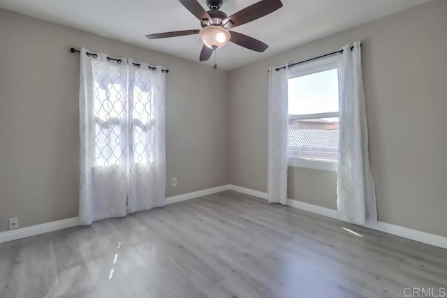 spare room featuring ceiling fan, baseboards, and wood finished floors