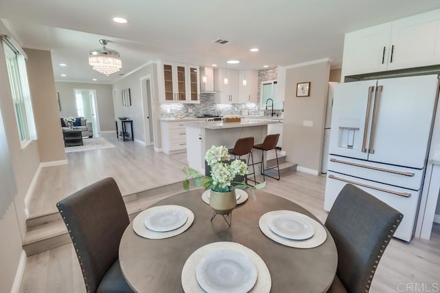 dining space featuring recessed lighting, crown molding, visible vents, light wood finished floors, and an inviting chandelier