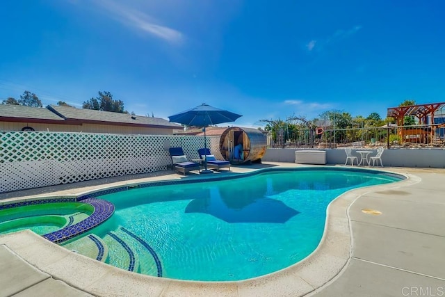 view of swimming pool with a pool with connected hot tub and fence