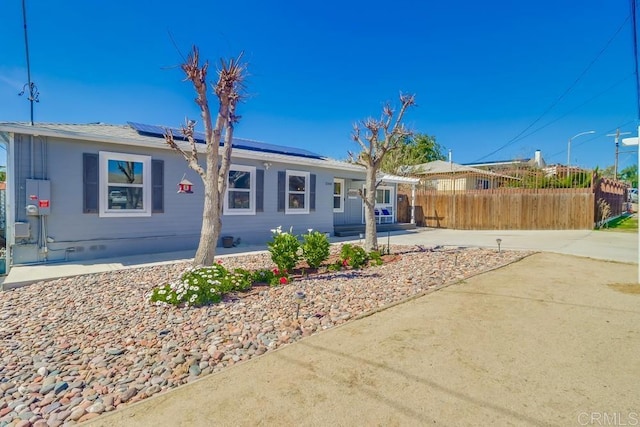 view of front of property with crawl space, fence, and roof mounted solar panels