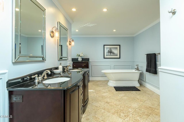 bathroom featuring a decorative wall, a freestanding bath, crown molding, and a sink