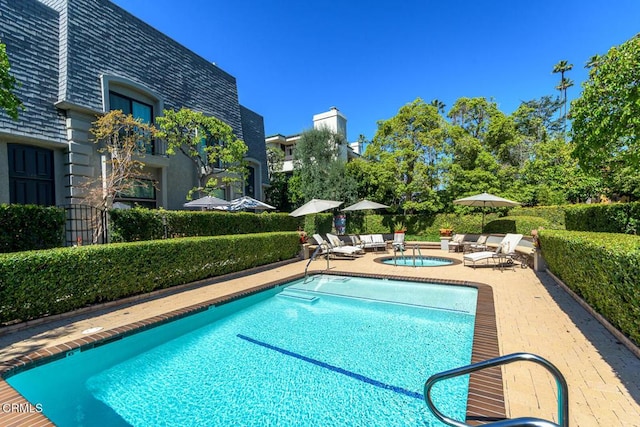 community pool with a patio and a hot tub