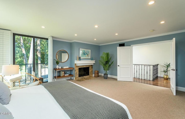 carpeted bedroom featuring a high end fireplace, baseboards, a wall of windows, ornamental molding, and recessed lighting