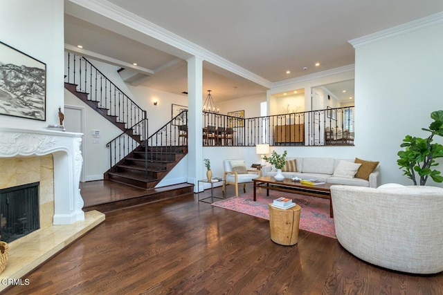 living area with stairway, wood finished floors, a high end fireplace, ornamental molding, and a chandelier