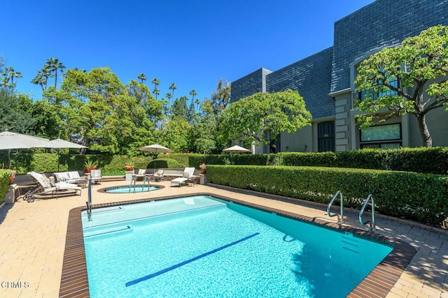 community pool with a patio area and a hot tub