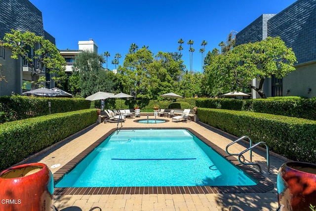 community pool with a hot tub and a patio