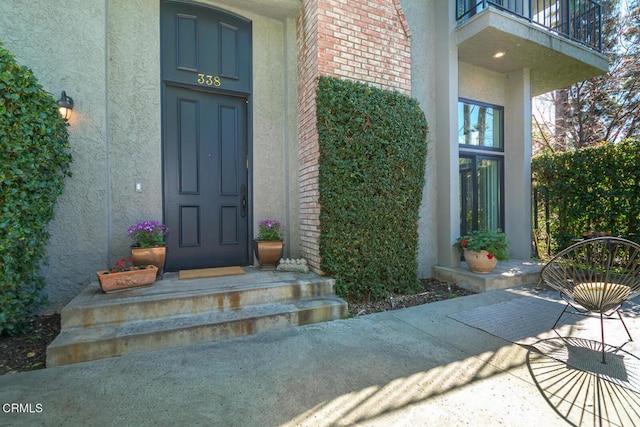 entrance to property featuring stucco siding and a balcony