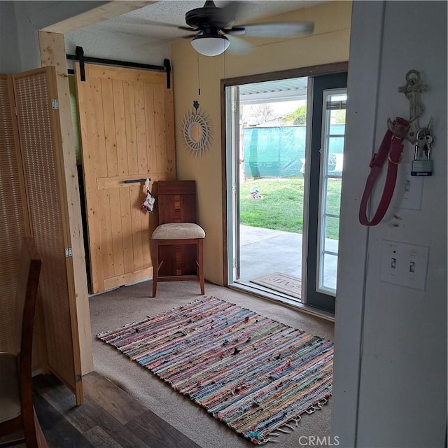 doorway to outside featuring a ceiling fan and a barn door