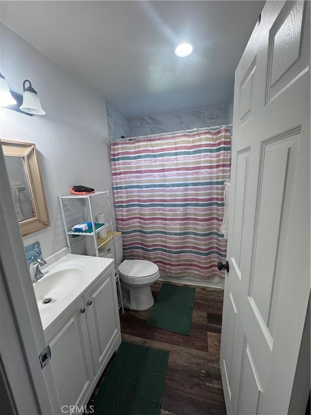 full bath with toilet, vanity, and wood finished floors