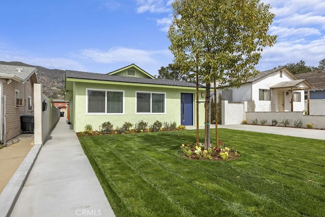 view of front facade featuring driveway, stucco siding, fence, and a front yard