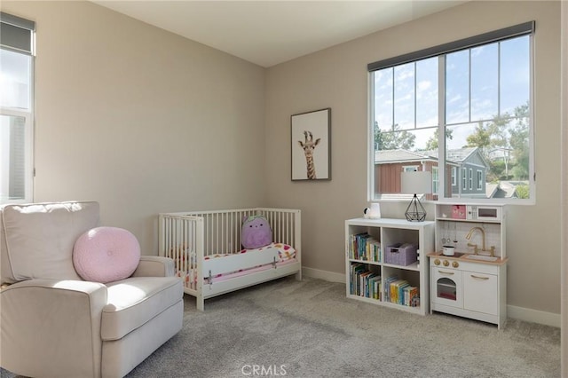 bedroom with carpet, baseboards, and a nursery area