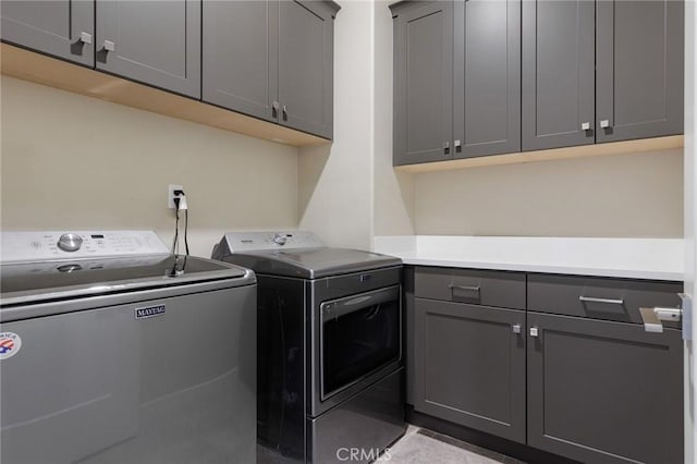 clothes washing area featuring washer and clothes dryer and cabinet space