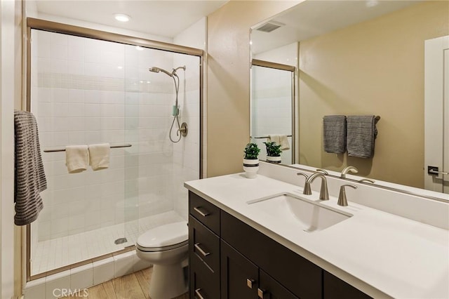 full bath with visible vents, toilet, vanity, a shower stall, and wood finished floors