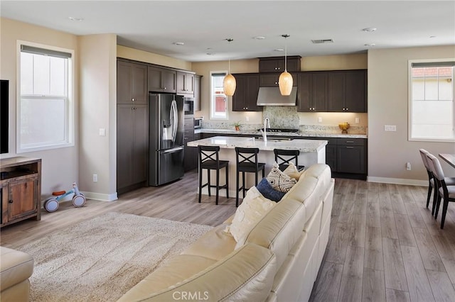 kitchen featuring appliances with stainless steel finishes, open floor plan, under cabinet range hood, and dark brown cabinets