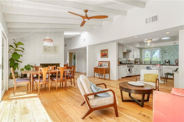 interior space with ceiling fan, light wood finished floors, beam ceiling, and visible vents