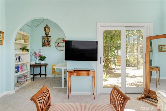 carpeted living area featuring built in shelves and baseboards