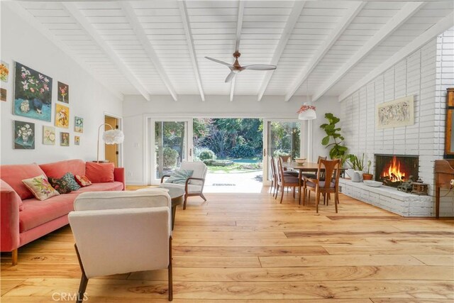 interior space with vaulted ceiling with beams, a fireplace, and a ceiling fan