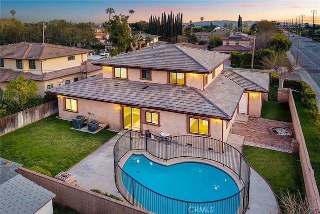 back of property with a fenced backyard, central air condition unit, a yard, a fenced in pool, and stucco siding