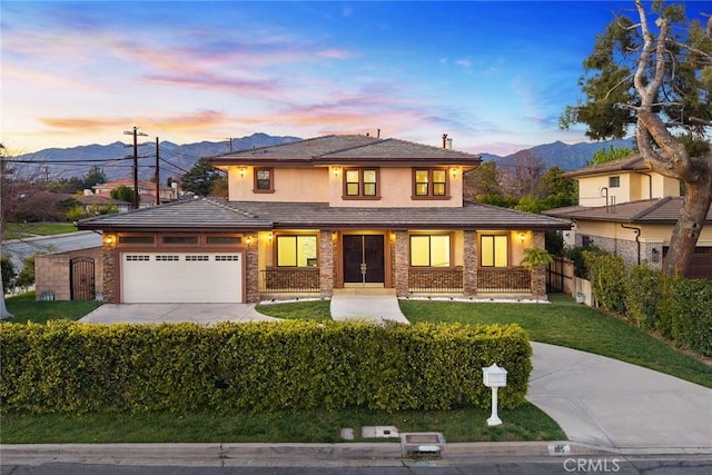 prairie-style house featuring an attached garage, a mountain view, fence, concrete driveway, and a front lawn