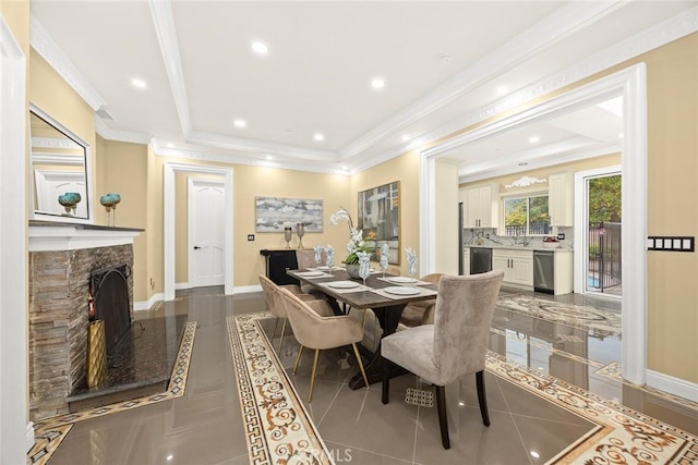 dining room featuring a warm lit fireplace, baseboards, and ornamental molding