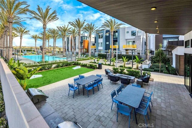 view of patio / terrace with a community pool, a fire pit, and outdoor dining area