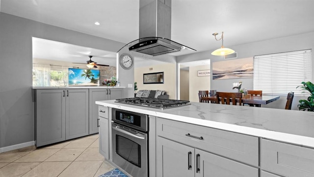 kitchen featuring light tile patterned floors, stainless steel appliances, hanging light fixtures, light stone countertops, and island exhaust hood