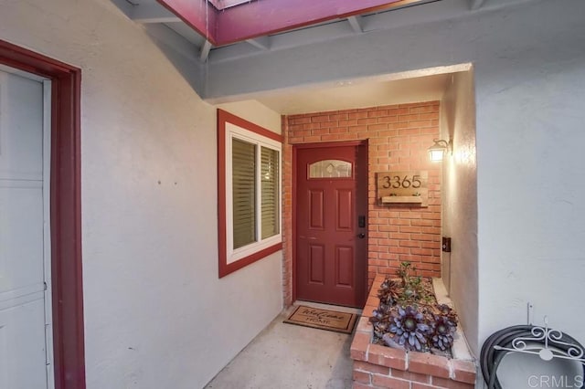 entrance to property featuring stucco siding and brick siding