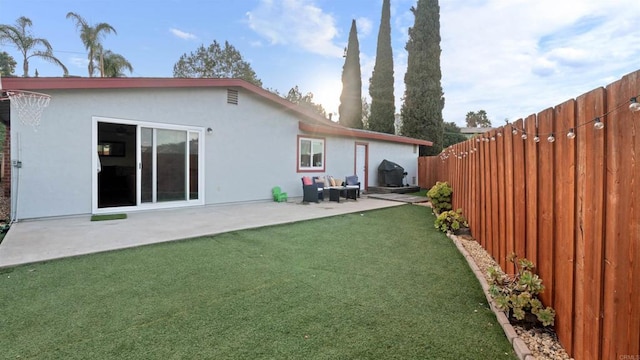 back of house with a lawn, a patio area, a fenced backyard, and stucco siding