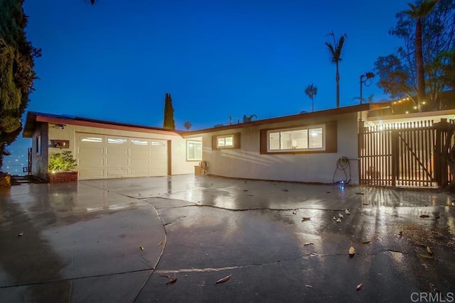 ranch-style house featuring an attached garage, fence, concrete driveway, and stucco siding