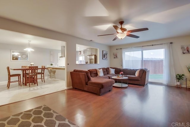 living area featuring ceiling fan, baseboards, and wood finished floors