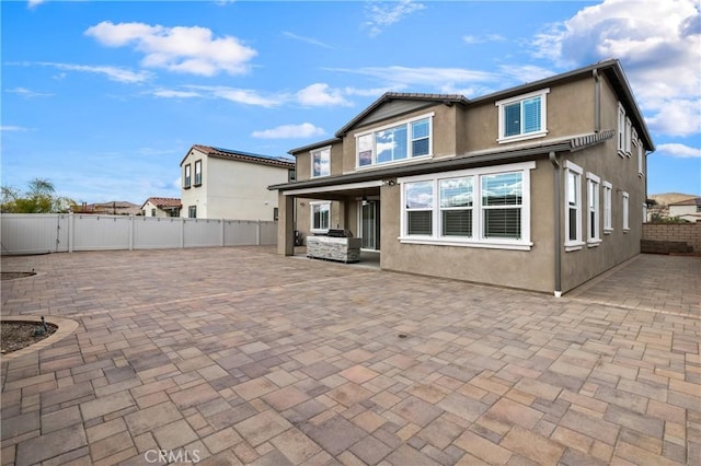 back of house featuring a patio, a fenced backyard, and stucco siding